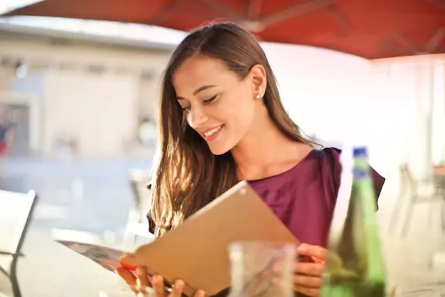 A woman smiling and looking at a menu