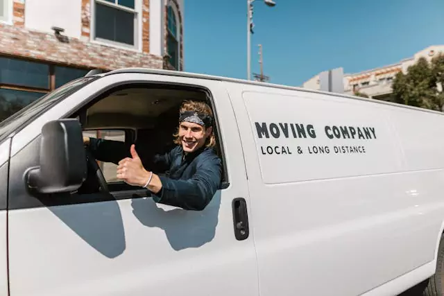 Moving company driver giving a thumbs up from a white van labeled "Local & Long Distance"