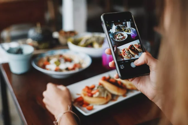 Woman taking a shot of food on a mobile phone during lunch